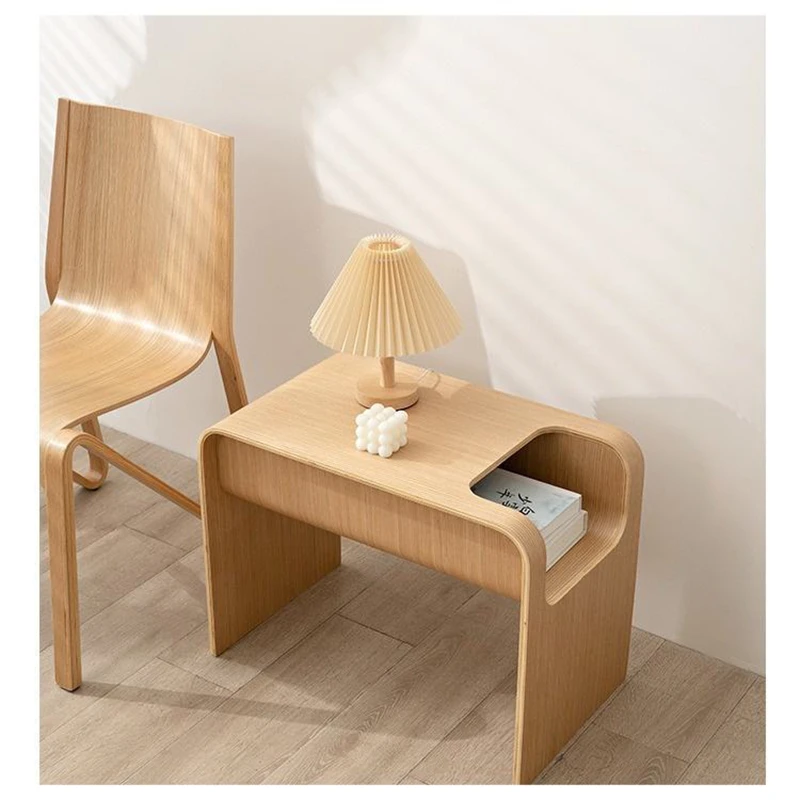 Manna natural bentwood side table with hollow magazine slot styled with a pleated table lamp and books in a modern bedroom.
