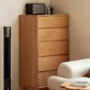 manna-cherry-wood-5-drawer-tall-dresser-living-room-corner Manna cherry wood 5-drawer tall dresser with fluted bottom drawer placed in a living room corner near a sofa.