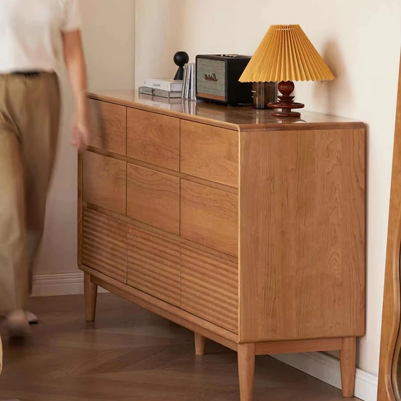 manna-cherry-wood-9-drawer-wide-dresser-side-view Side angle view of Manna cherry wood 9-drawer wide dresser with fluted bottom drawers in a brightly lit room.