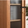 Close-up detail of fluted glass door with a solid brass knob handle on Manna cherry wood cabinet.