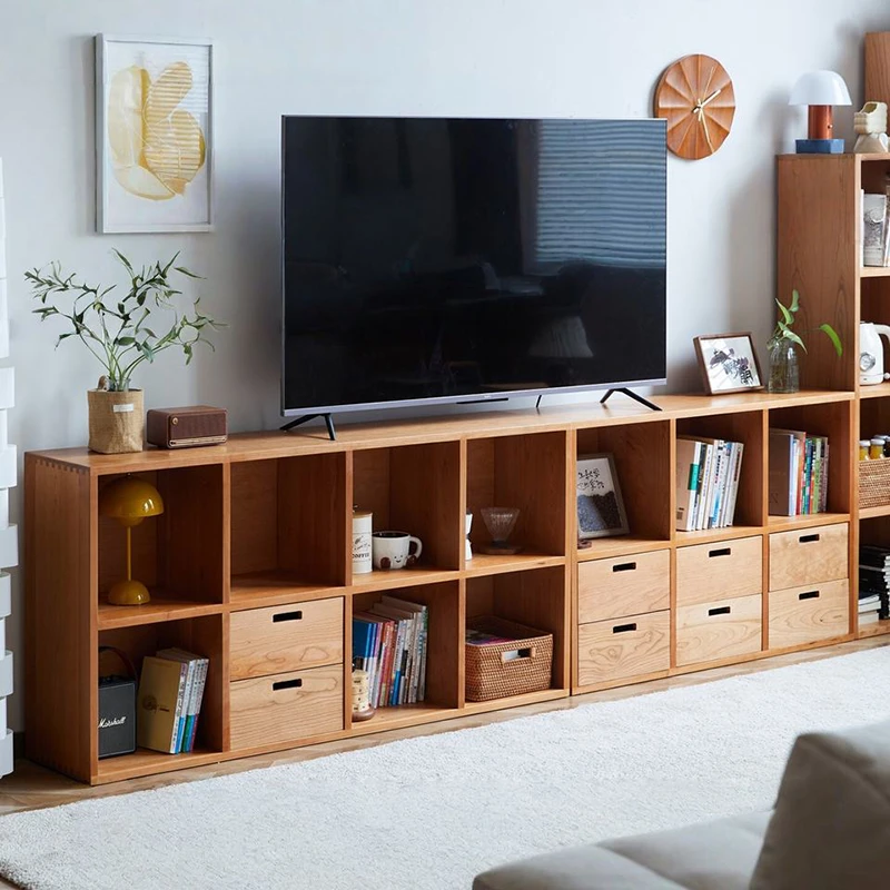 Manna cherry wood modular bookcase used as a low TV stand with storage cubes and drawers in a bright living room.