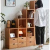 manna-cherry-wood-modular-step-cube-bookcase-lifestyle A person selecting a book from a Manna cherry wood modular step cube bookcase in a modern living space.