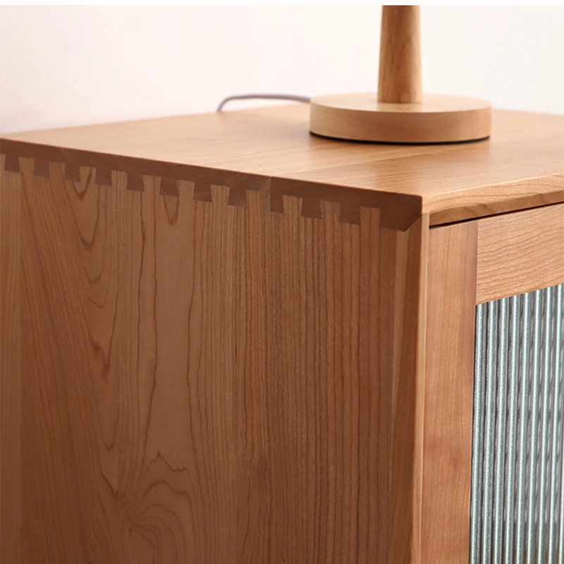 Close-up view of traditional dovetail joint craftsmanship on top corner of Manna cherry wood narrow cabinet.