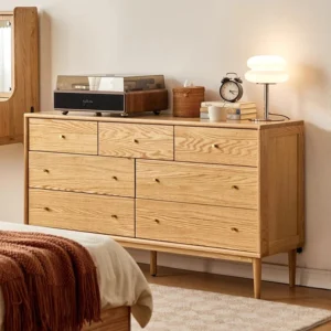 manna-oak-7-drawer-wide-dresser-bedroom-setup Manna oak 7-drawer wide chest of drawers styled in a sunlit bedroom next to a bed with a record player and mushroom lamp.