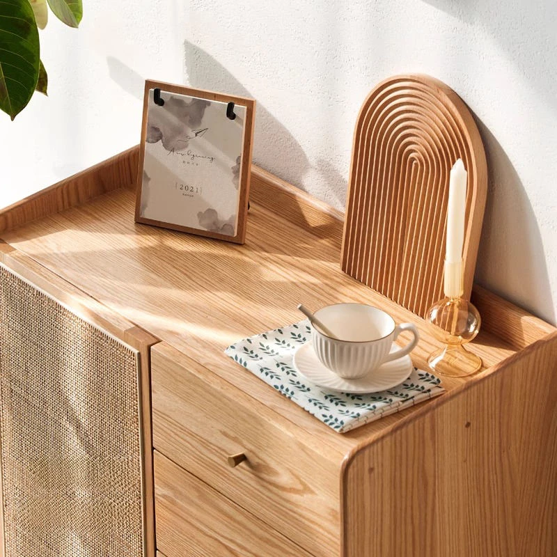 manna-oak-accent-cabinet-tabletop-gallery-rail-detail Close-up top view of Manna oak accent cabinet tabletop with raised lip edges, holding a coffee cup, calendar, and candle.