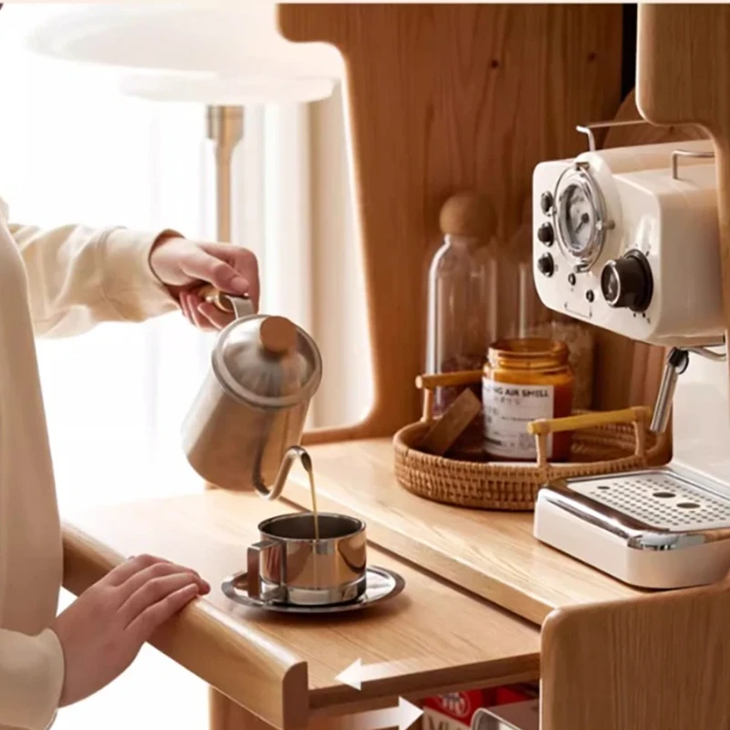 Close-up view of pull-out extension shelf on Manna oak coffee bar cabinet with a person pouring coffee from a kettle.