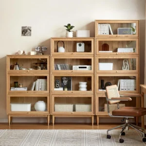 Manna oak glass door bookcases in 3-tier, 4-tier, and 5-tier configurations arranged side-by-side in a modern home office with a desk chair.
