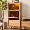 manna-oak-glass-flip-door-bookcase-led-light-living-room Manna oak glass flip door bookcase with interior warm LED lighting styled next to a vinyl record player in a living room.