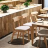 Set of Manna solid oak horn-back dining chairs with cream upholstered cushions styled in a modern restaurant setup.