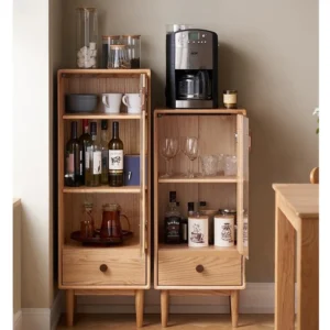Front view of Manna oak narrow glass cabinets with open glass doors showcasing organized wine bottles, glasses, and a coffee machine on top.