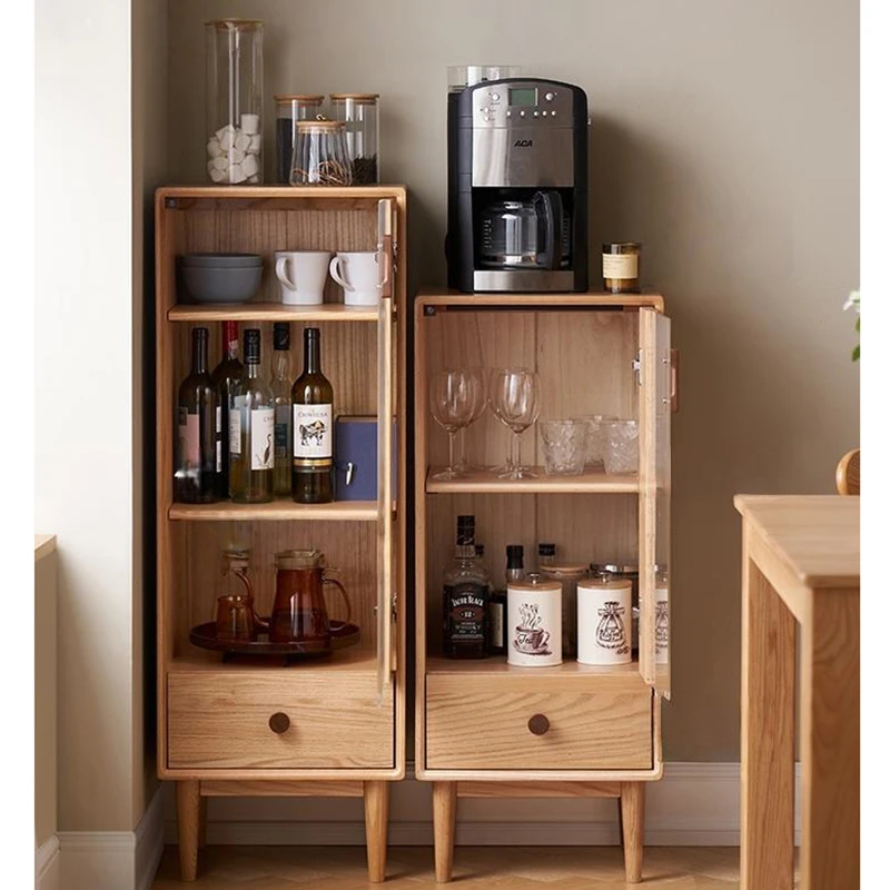Front view of Manna oak narrow glass cabinets with open glass doors showcasing organized wine bottles, glasses, and a coffee machine on top.