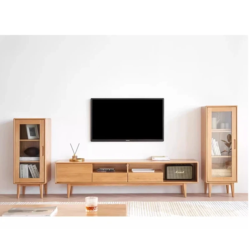 Two Manna oak narrow glass display cabinets in different heights flanking a matching wooden TV media console in a living room.