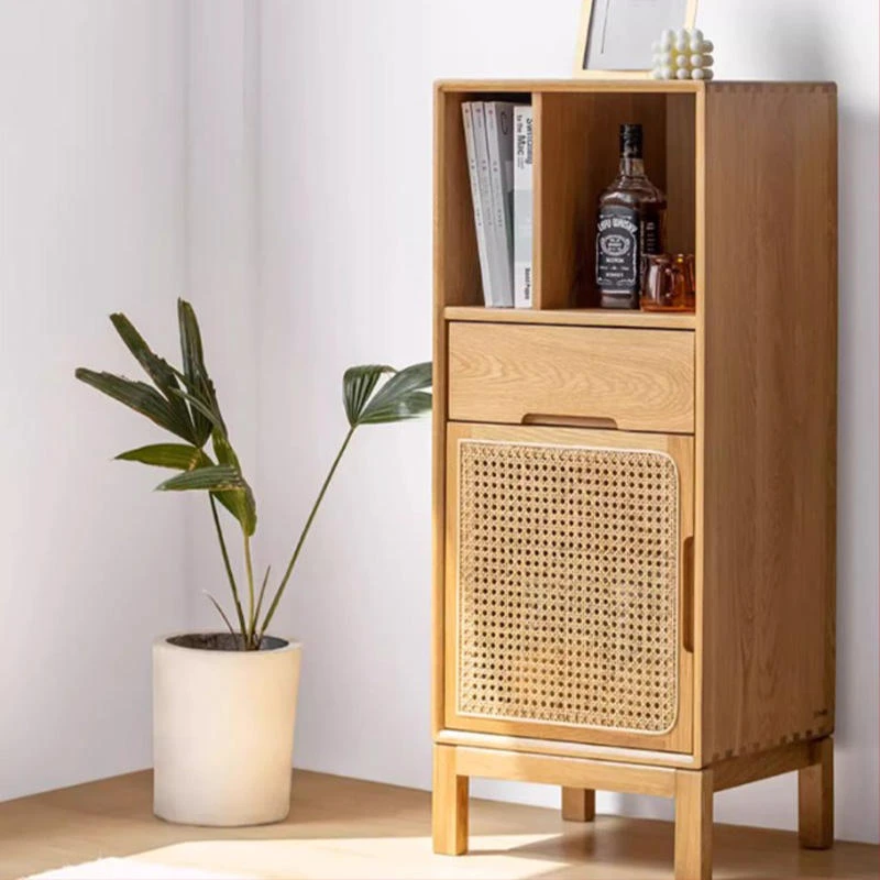 Front view of Manna oak narrow cabinet featuring rattan mesh door, drawer, and open top shelves holding books and a whiskey bottle.