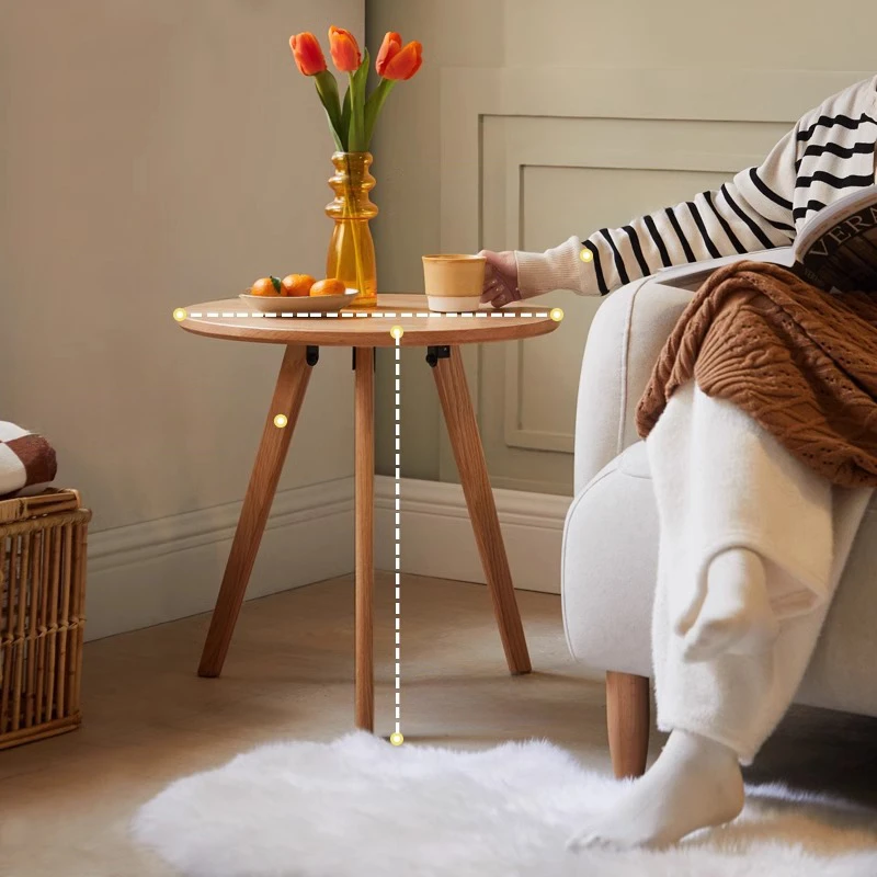 Manna oak round side table placed next to a person sitting on an armchair, showing ergonomic side table height for coffee cups.