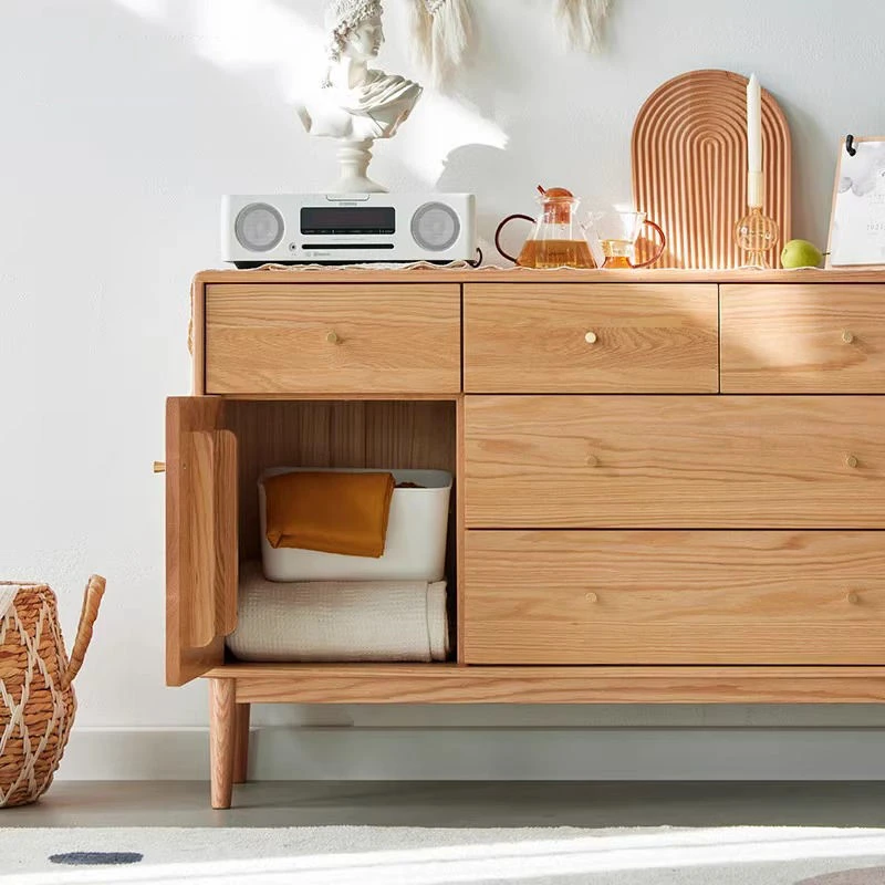 Close-up view of open single door cabinet compartment on Manna oak sideboard credenza holding storage bins and blankets.