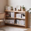 Manna oak slim low bookcase with 22cm depth placed against a wall filled with books and storage boxes in a study room.
