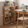Manna oak ultra-slim 10cm deep bookcase placed beside a wooden study desk in a child's bedroom.