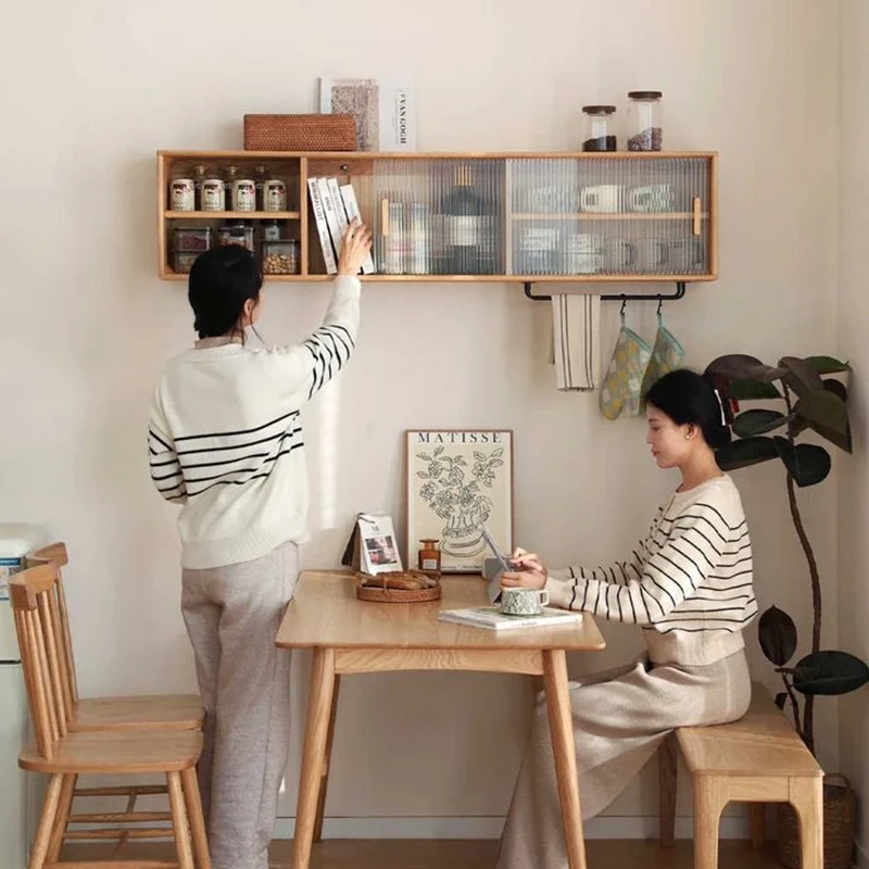 Two people interacting with Manna oak wall-mounted cabinet and dining table setup in a cozy home.