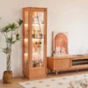 manna-turin-cherry-wood-glass-display-cabinet-living-room Manna Turin cherry wood glass display cabinet with built-in LED lighting holding collectibles and liquor bottles in a living room.