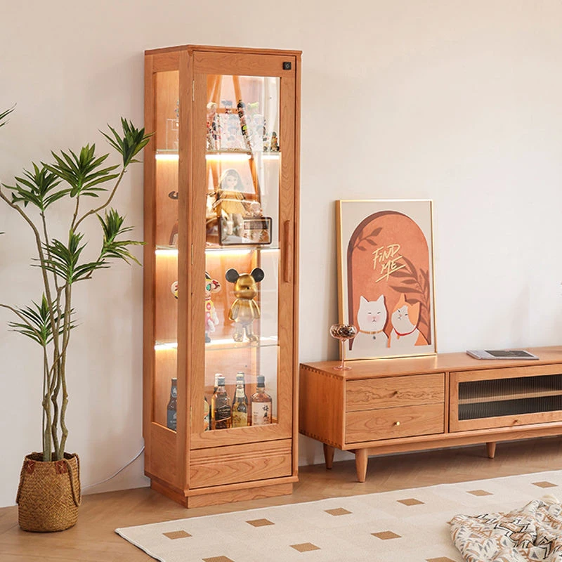 manna-turin-cherry-wood-glass-display-cabinet-living-room Manna Turin cherry wood glass display cabinet with built-in LED lighting holding collectibles and liquor bottles in a living room.