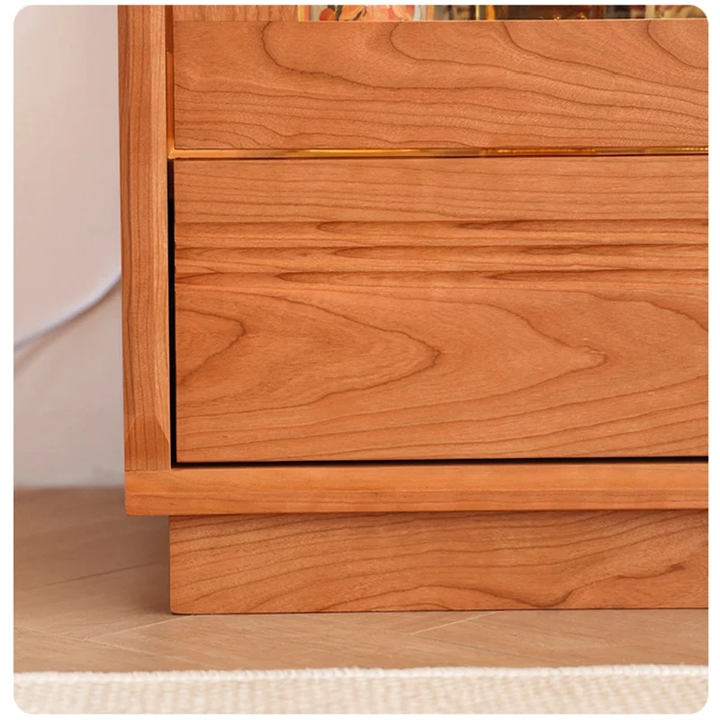 Close-up view of the bottom solid wood storage drawer and stable plinth base on Manna Turin cherry wood display cabinet.
