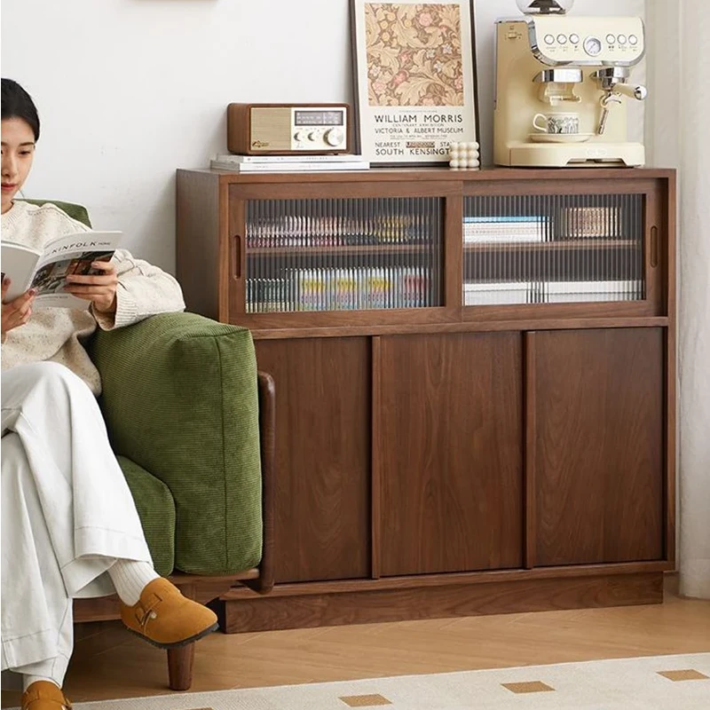 Manna black walnut credenza sideboard with glass sliding doors placed next to a sofa in a cozy living room.