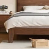 solid-walnut-bed-frame-corner-and-nightstand Crafted solid black walnut bed foot and side rail detail paired with a matching wooden nightstand.