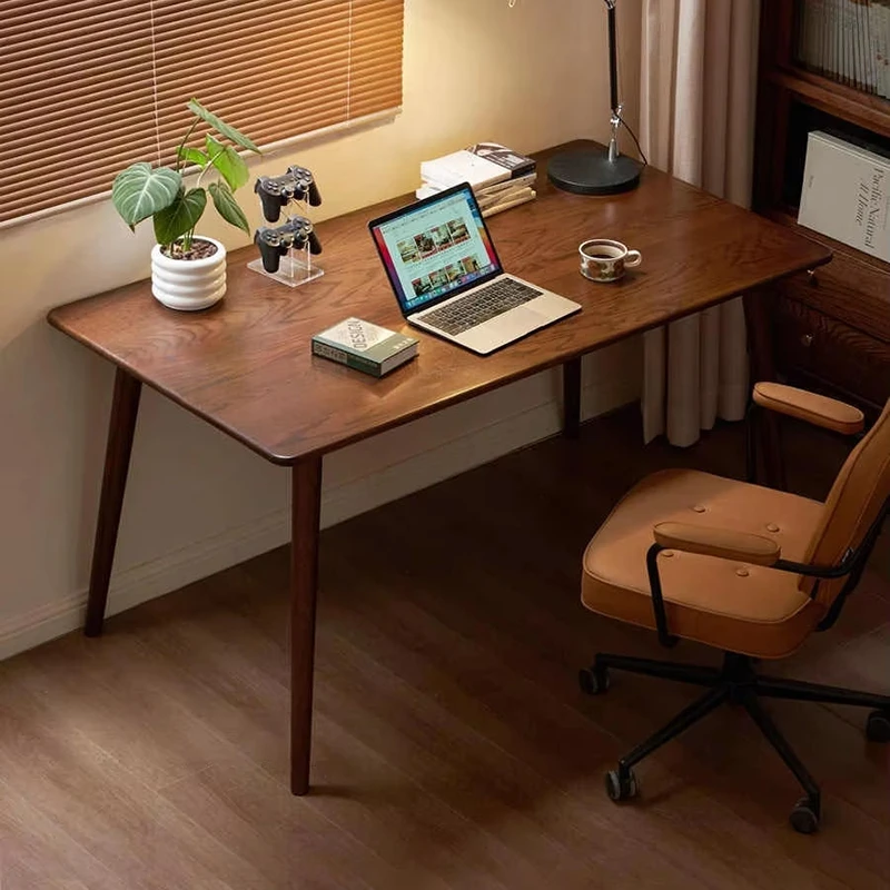 Dark wood study computer desk with laptop, green potted plant, and ergonomic leather chair in a cozy home office.