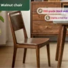 manna-black-walnut-dining-chair-lifestyle FAS grade black walnut dining chair with an arched high back beside a wooden sideboard in a dining room.