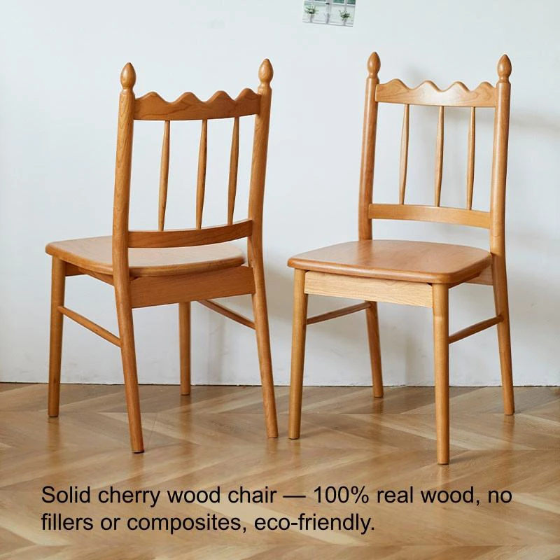 manna-cherry-dining-chair-spindle-back-front-view Front view of two solid cherry wood dining chairs with spindle backs and carved crests against a white wall.