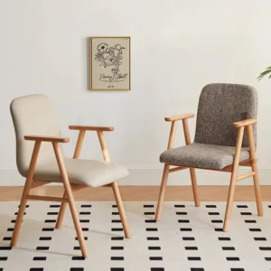 Lifestyle view of two oak dining armchairs with upholstered backs and seats in beige leather and grey fabric.