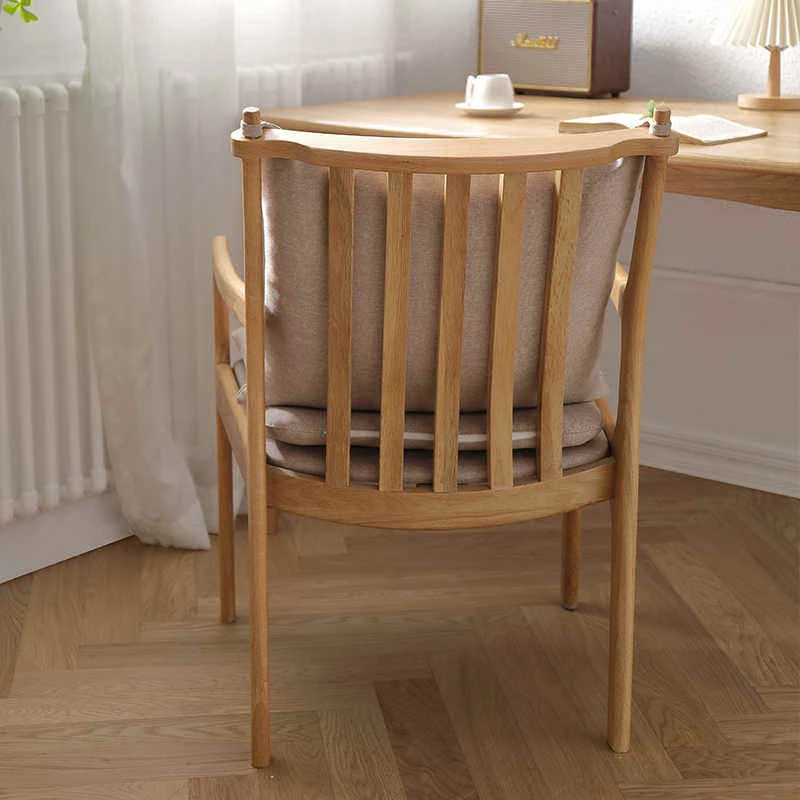manna-oak-armchair-spindle-back-back-view Back view of natural oak dining armchair showing vertical spindle backrest, curved crest rail and beige seat cushion straps.
