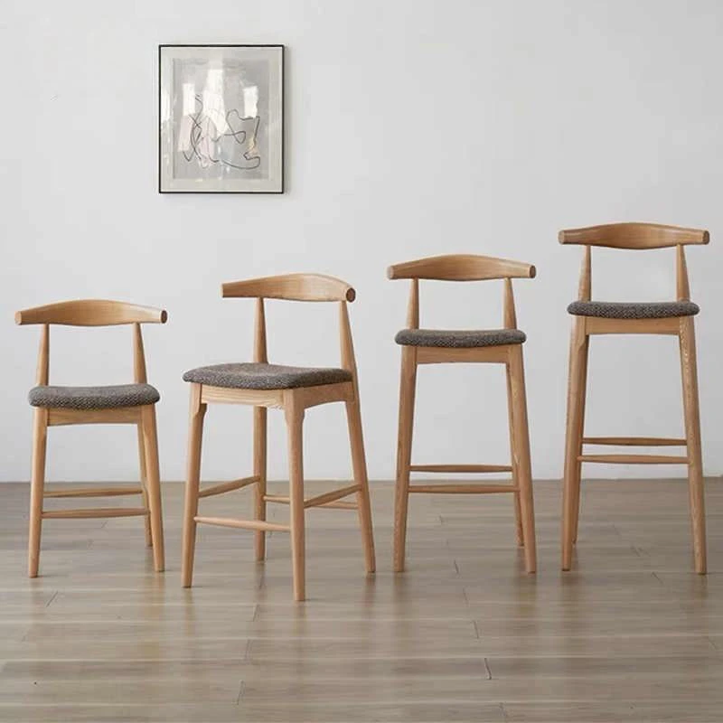 manna-oak-bar-stool-woven-seat-size-guide Four oak bar stools with grey woven upholstered seats in increasing counter, bar and extra tall heights against a white wall.
