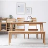 manna-oak-dining-bench-dining-room-cd1004 Oak dining bench placed in front of an oak dining table with two spindle chairs in a bright modern dining room.