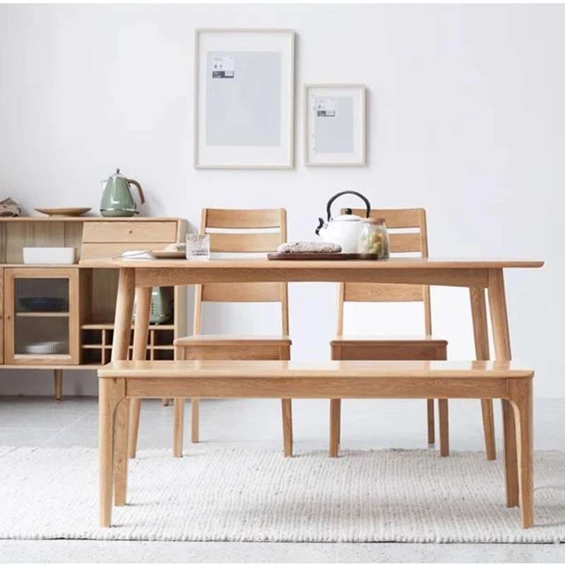 manna-oak-dining-bench-dining-room-cd1004 Oak dining bench placed in front of an oak dining table with two spindle chairs in a bright modern dining room.