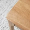 manna-oak-dining-bench-material-detail-cd1004 Close-up of a solid oak bench top showing the rounded corner and natural light oak grain beside a woven rug.