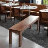 manna-oak-dining-bench-restaurant Warm red brown oak dining bench with square straight legs placed in a modern restaurant beside round tables.