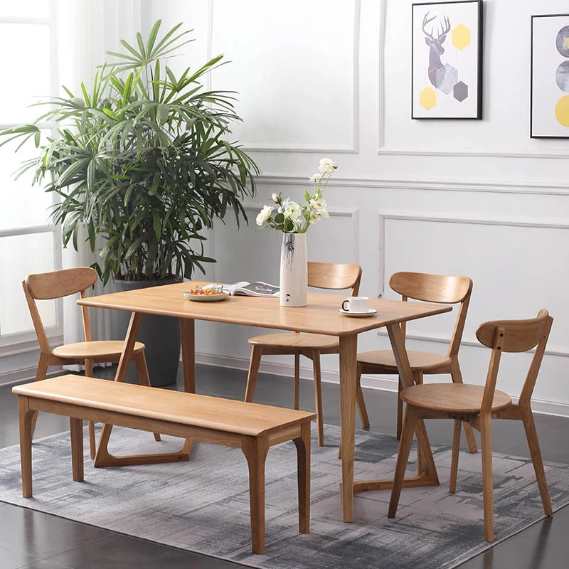 manna-oak-dining-chair-curved-back-dining-room Lifestyle view of oak dining set with wooden table, bench and four curved back oak chairs on a grey rug.