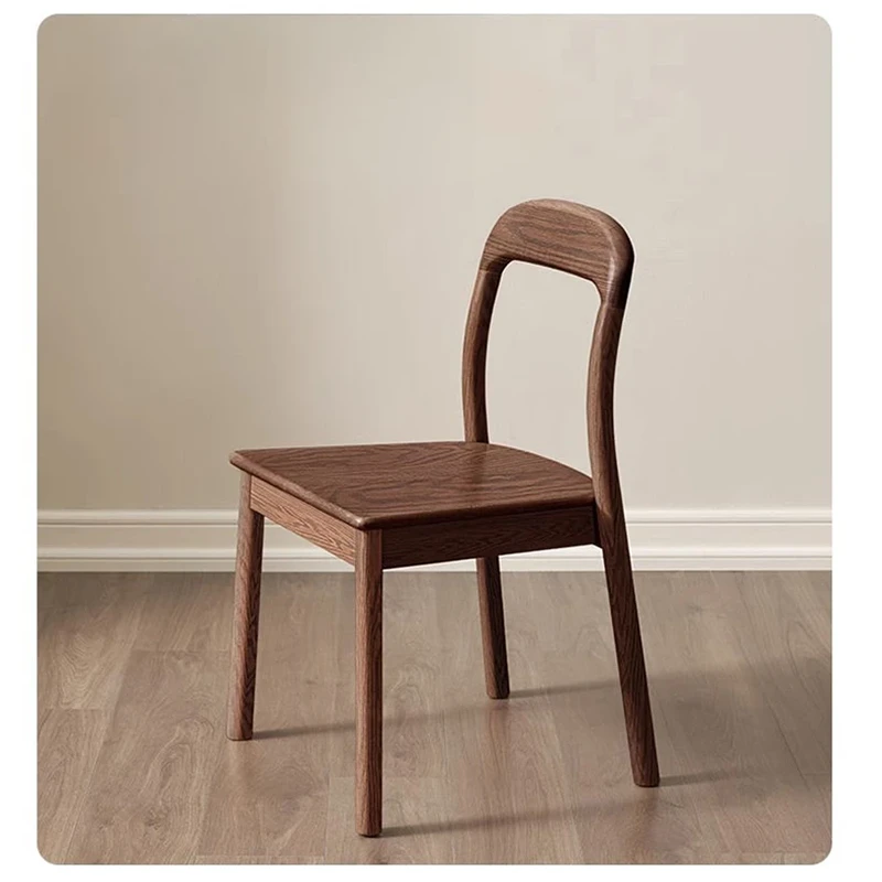 Front view of an oak dining chair with a rounded open backrest and contoured solid wood seat on a pale wood floor.