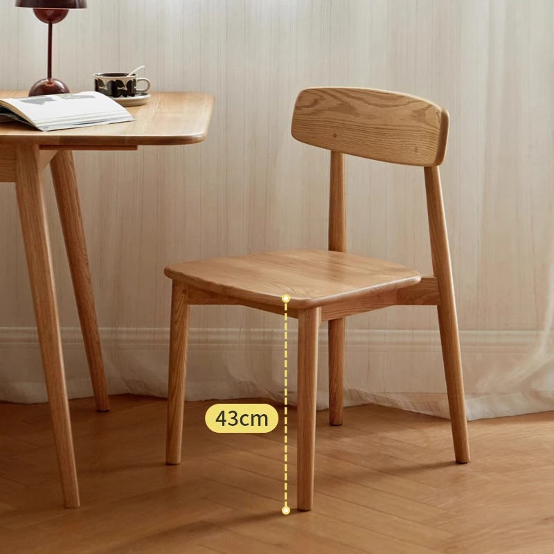 Detail view of an oak dining chair with a 43cm seat height dimension line marked on a wooden herringbone floor.