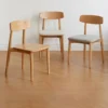 Three oak dining chairs with curved backrests shown with solid wood, cream fabric and grey fabric seat options.