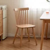 Front view of solid oak dining chair with seven spindle backrest and solid wood seat beside a small table.