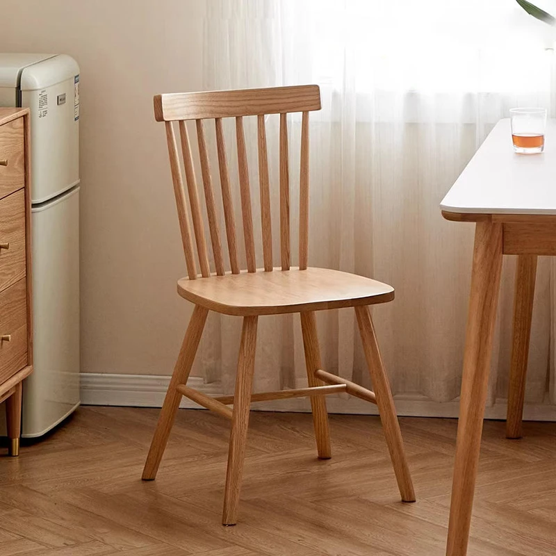 Front view of solid oak dining chair with seven spindle backrest and solid wood seat beside a small table.