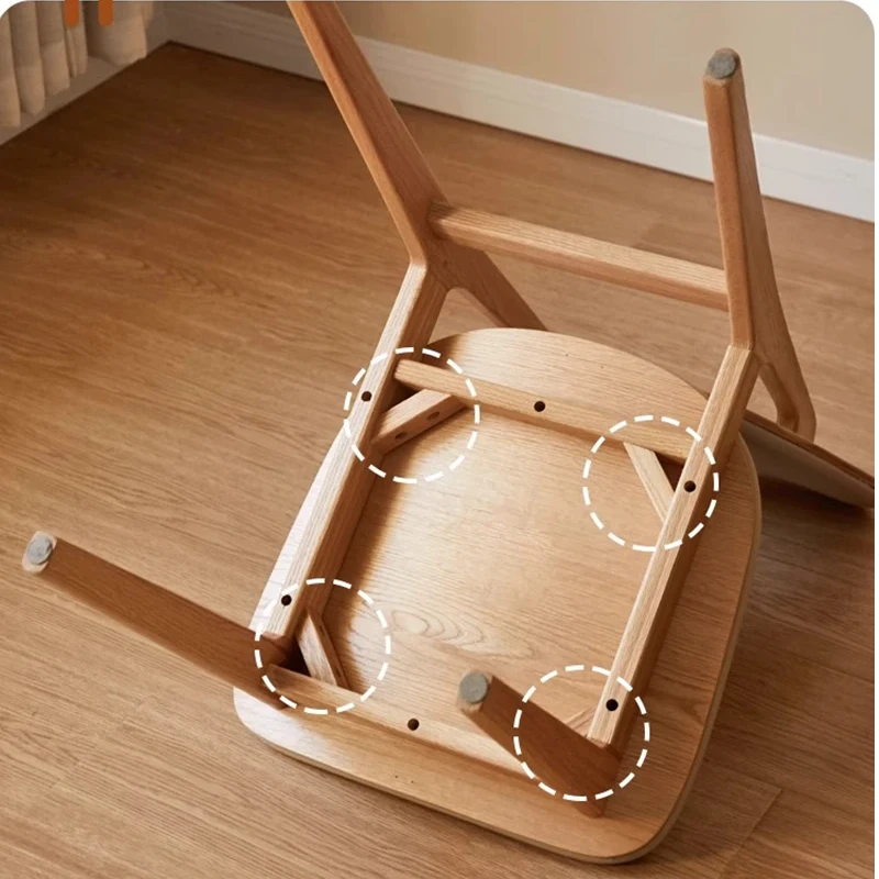 Detail view of the underside of an oak dining chair showing the solid wood seat frame and leg joint construction.
