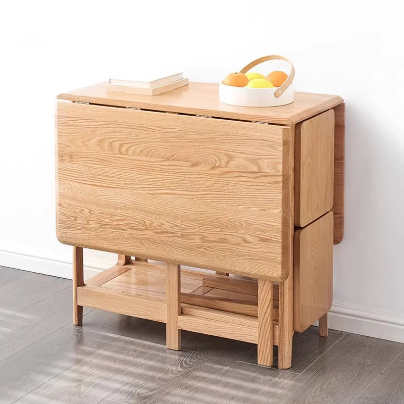 Lifestyle scene of an oak folding dining table with both hinged leaves dropped into a compact sideboard shape.