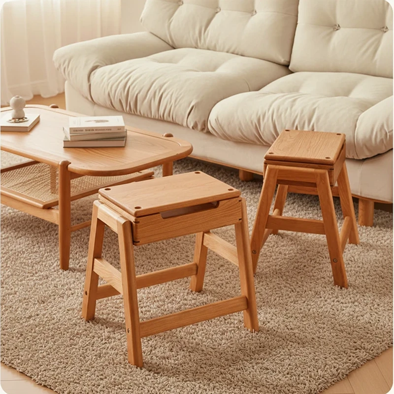 Two solid oak folding step stools with fold open storage seats standing on a beige rug beside a wooden coffee table.