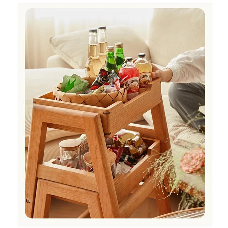 Detail view of oak folding step stool opened into a two tier storage side table holding bottles and snack baskets.