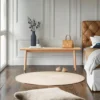 manna-oak-rattan-dining-bench-front-view Front view of a natural oak bench with woven rattan cane seat and tapered legs against a panelled white wall.