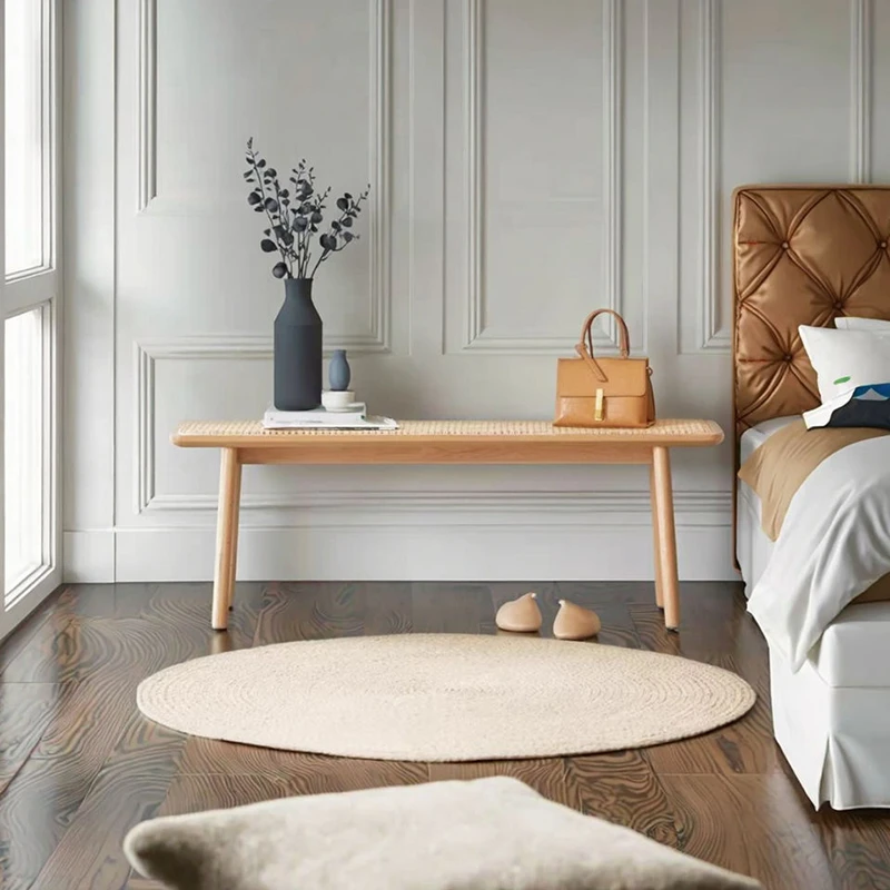 manna-oak-rattan-dining-bench-front-view Front view of a natural oak bench with woven rattan cane seat and tapered legs against a panelled white wall.