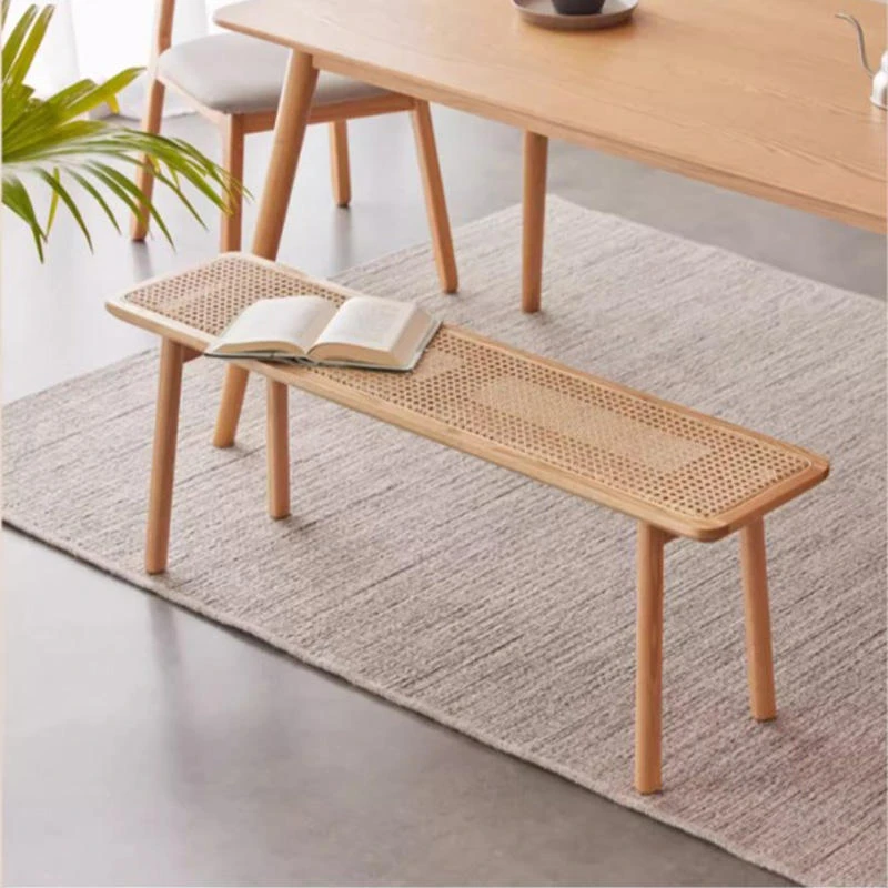 manna-oak-rattan-dining-bench-lifestyle Lifestyle view of a natural oak dining bench with a woven rattan cane seat and tapered round legs beneath a dining table.